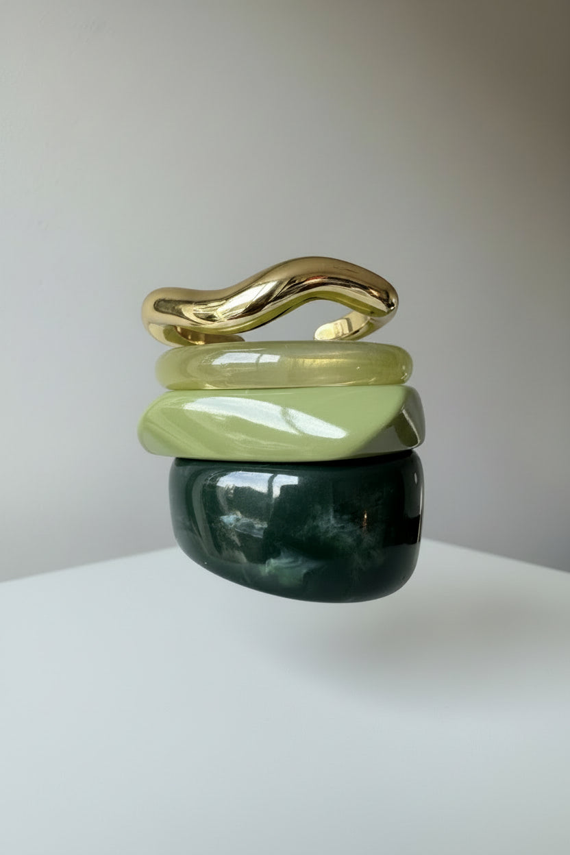 Stack of green acrylic resin bangles and gold metal bangles