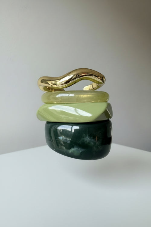 Stack of green acrylic resin bangles and gold metal bangles